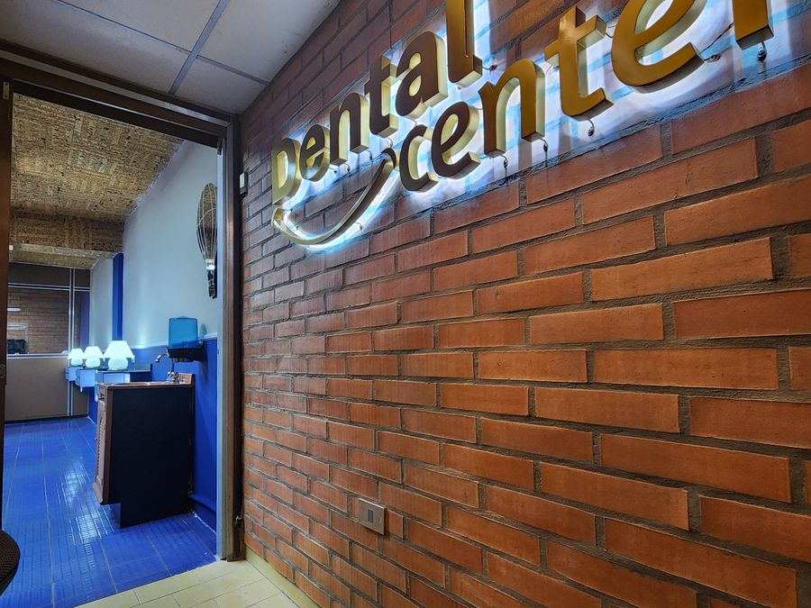 Pared de ladrillo con el logo de Dental Center iluminado